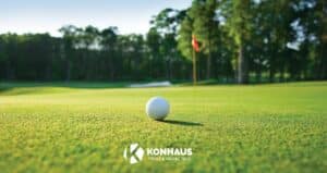 Image of a golf ball on the green near the pin with Konhaus logo